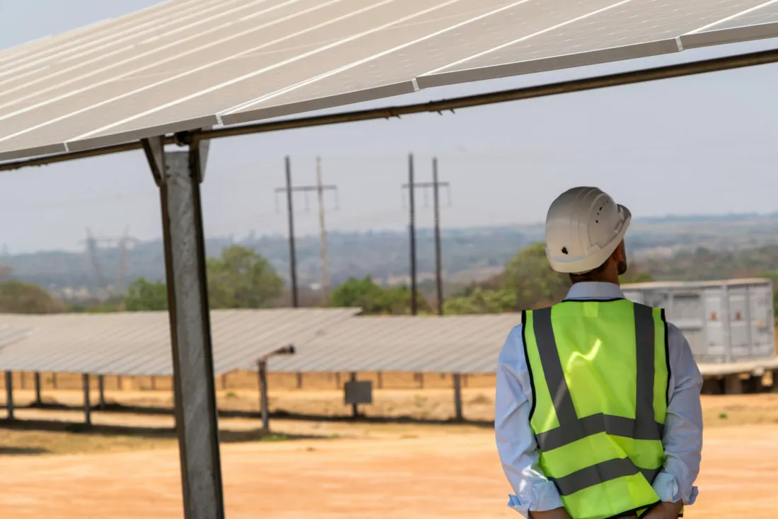 Técnico con chaleco reflectante frente a una planta fotovoltaica