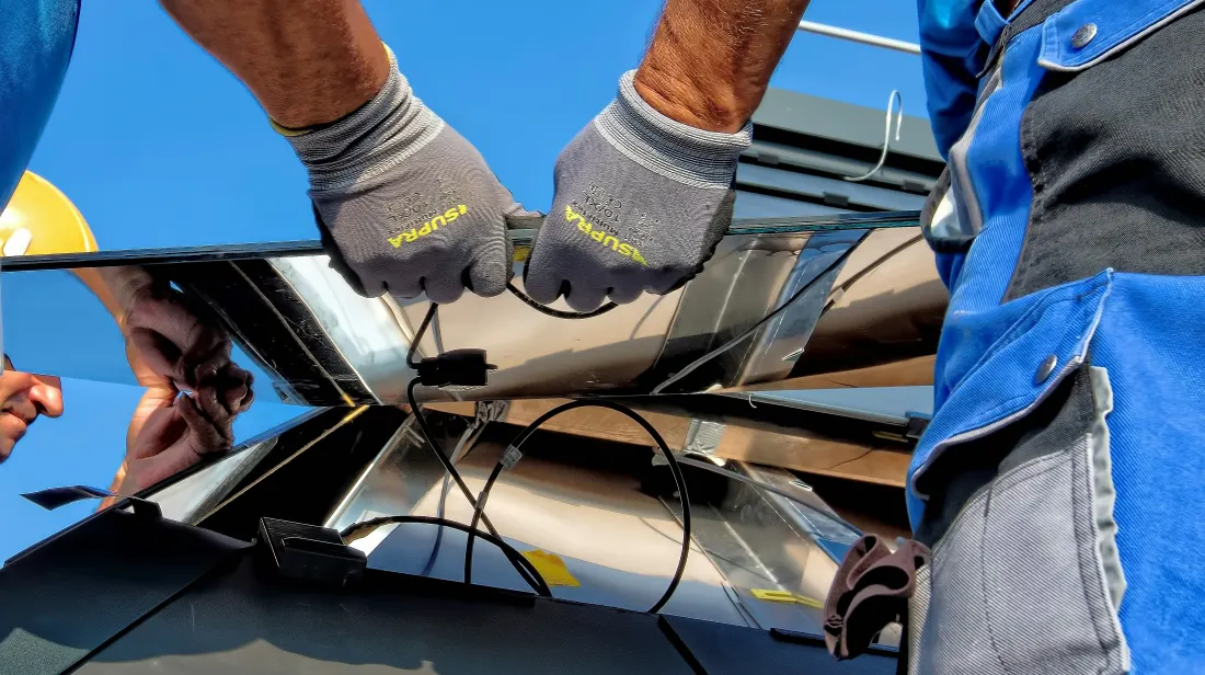 Dos técnicos instalando la estructura de un panel solar en un techo
